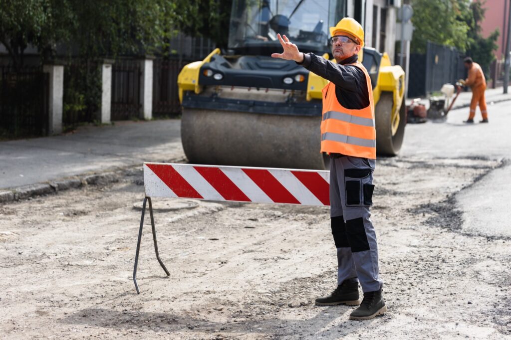 Agent en casque et gilet haute visibilité assurant le balisage et la signalisation d'un chantier de travaux sur réseaux