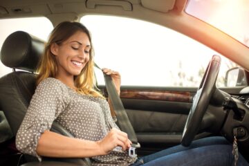 Conductrice attachant sa ceinture de sécurité avant de prendre la route pour les vacances